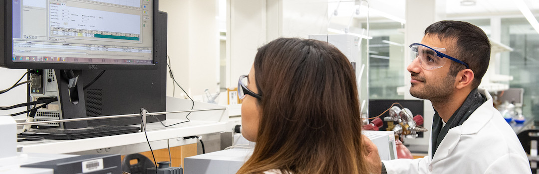 Man and woman in lab looking at computer screen