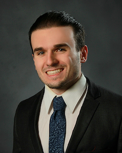 Noah Roberson head and shoulders photo, in suit and tie with dark background