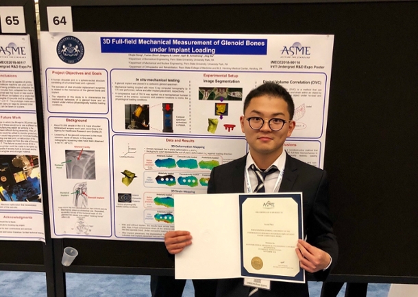 Chujie Gong with his award standing in front of his poster at conference