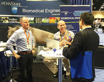 Justing Brown and Will Hancock at Penn State booth sharing with person